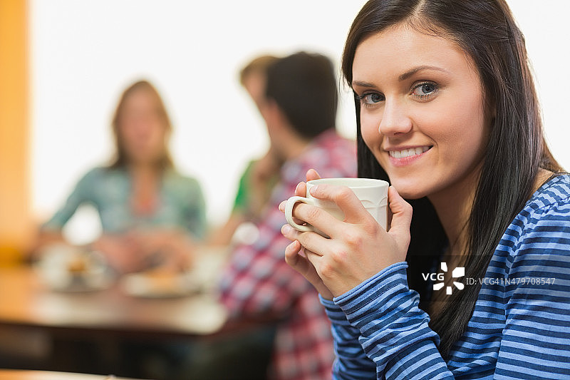 一个微笑的女性在咖啡店喝咖啡的肖像图片素材