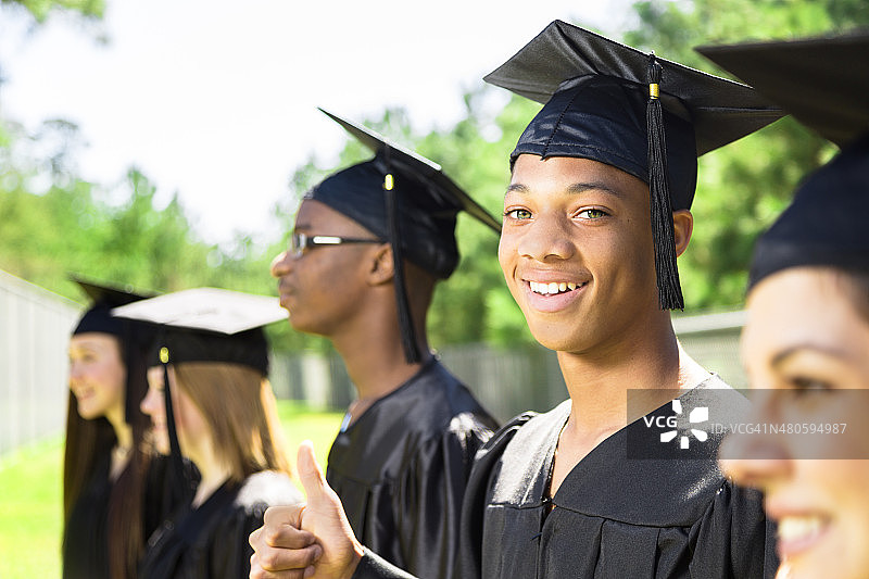教育背景:非洲裔男性和毕业时的朋友。帽,礼服。图片素材