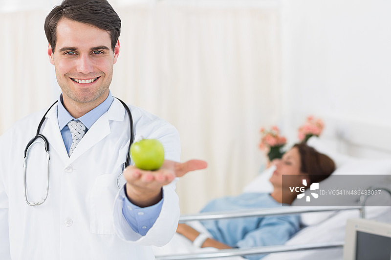 微笑的医生拿着苹果与病人在医院图片素材