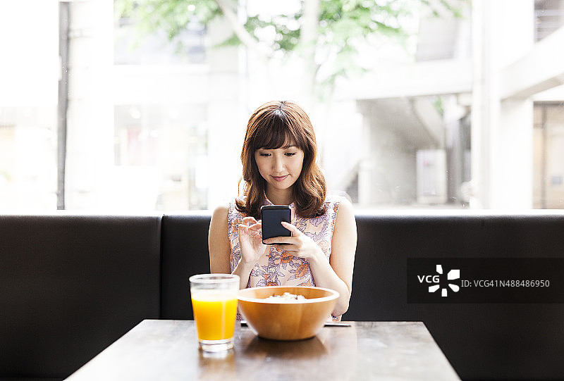 亚洲女孩在吃午饭时使用智能手机图片素材