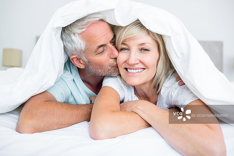 成熟的男人亲吻女人的脸颊在床上的特写图片素材