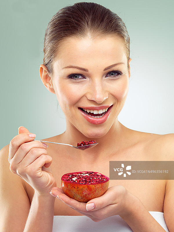漂亮的年轻女子用茶匙吃葡萄柚图片素材
