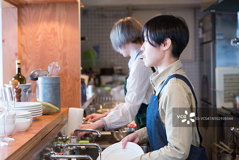 年轻的日本女士在厨房工作图片素材