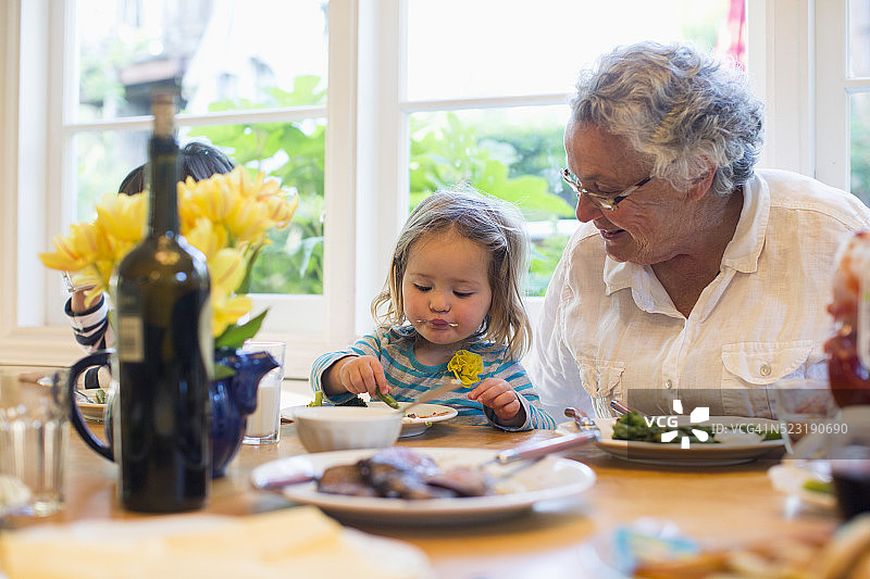 美国加州，小女孩(2-3岁)和奶奶一起吃晚饭图片素材