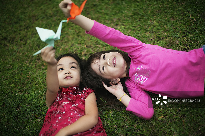 女孩们躺在草地上玩折纸图片素材