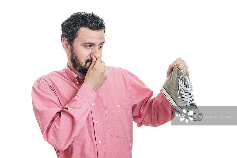 男人拿着脏臭的鞋子。不愉快的气味臭图片素材