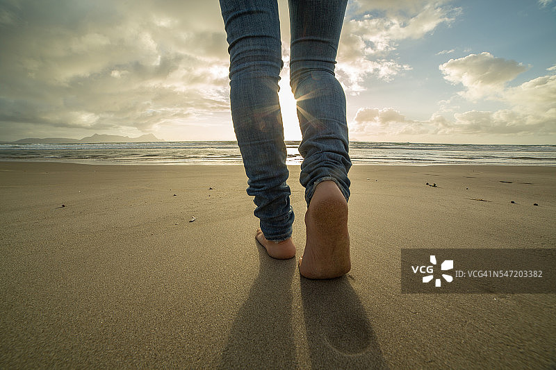 近距离拍摄在沙滩上行走的女人的脚，阳光图片素材