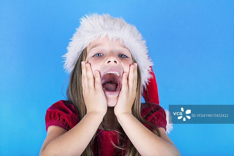 可爱的小女孩戴着圣诞帽在圣诞节给你一个惊喜图片素材