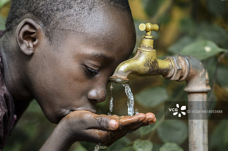 非洲小男孩从水龙头里喝健康干净的水图片素材