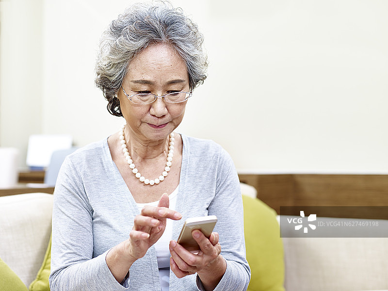 年长的亚洲女性使用手机图片素材