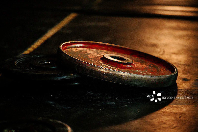 在黑暗的地板上放置举重比赛用杠铃的盘子图片素材