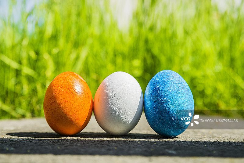 3个五彩缤纷的复活节彩蛋在草地上排成一排图片素材