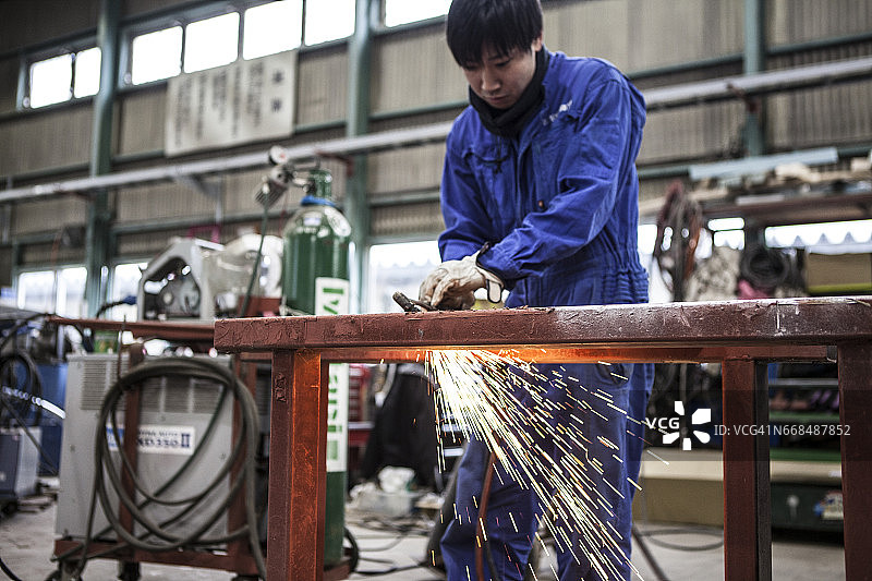 年轻工人在工厂切割钢材图片素材