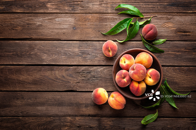 新鲜多汁的桃子与叶片在深色木制乡村背景图片素材