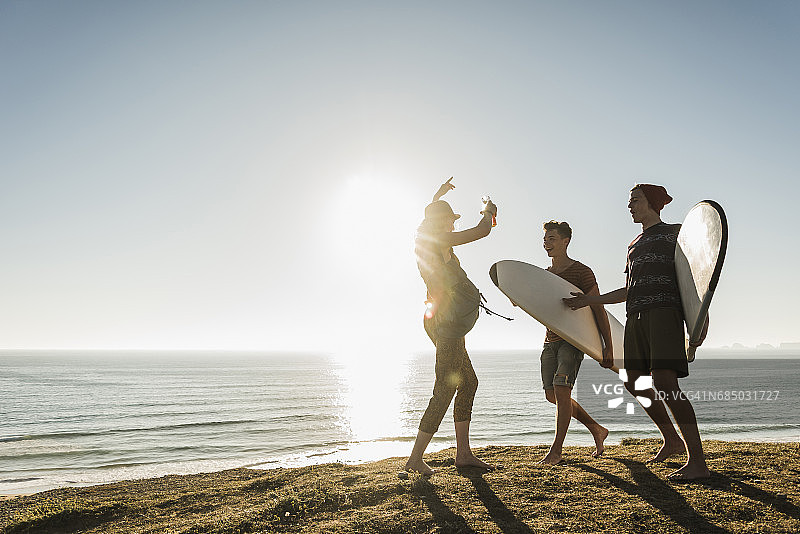 三个带着冲浪板的朋友在海边露营图片素材