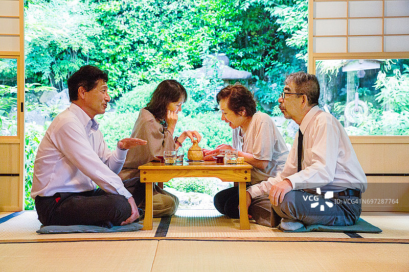四位成熟的日本老人在花园餐厅享受社交聚会图片素材