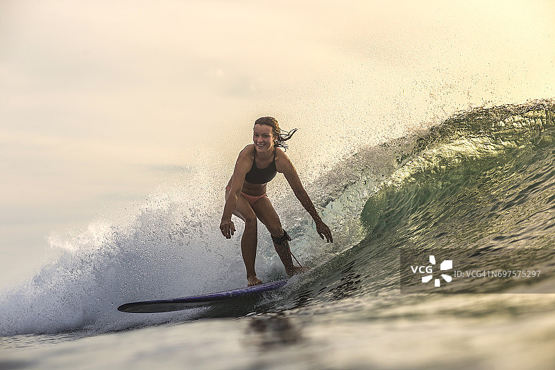 印度尼西亚，巴厘岛，女人在日落时冲浪图片素材