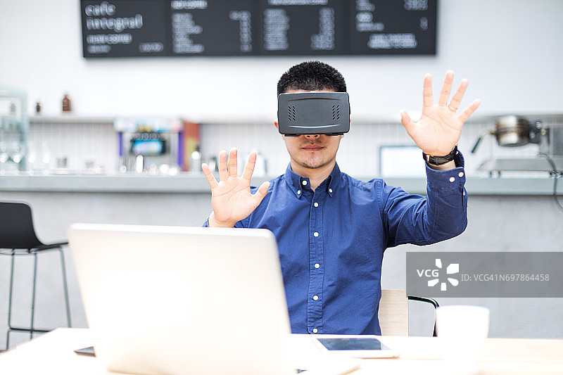 年轻的亚洲男人在现代咖啡馆用VR图片素材