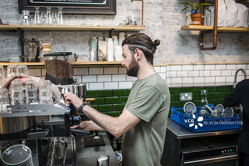 年轻的男咖啡师在咖啡厅厨房准备咖啡图片素材
