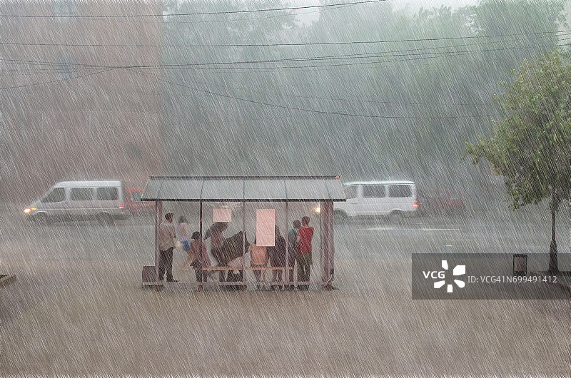 一群人在城市的一个车站躲避大雨。图片素材