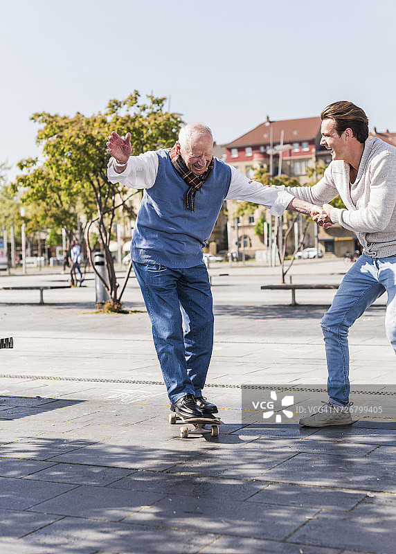 成年孙子协助老人玩滑板图片素材