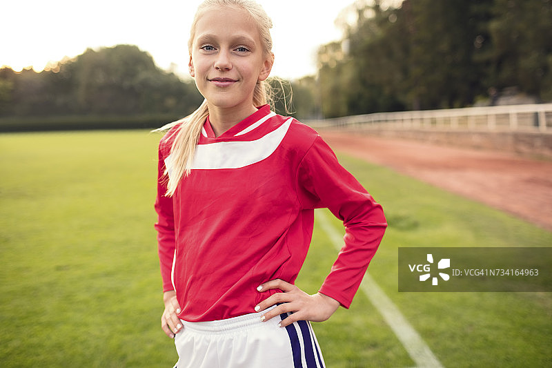 一个自信的女孩双手叉腰站在足球场上图片素材