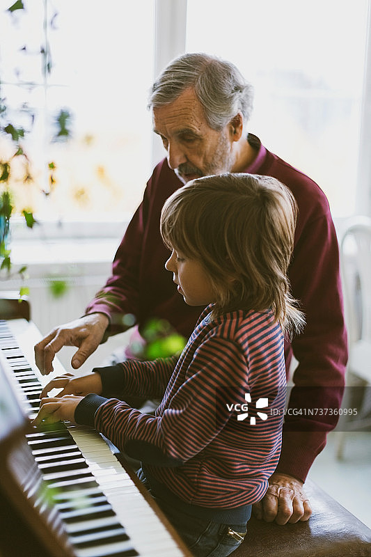 男孩和曾祖父一起在家里弹钢琴图片素材