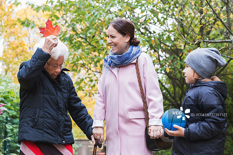 母子俩在公园里看着老女人抱着秋叶图片素材
