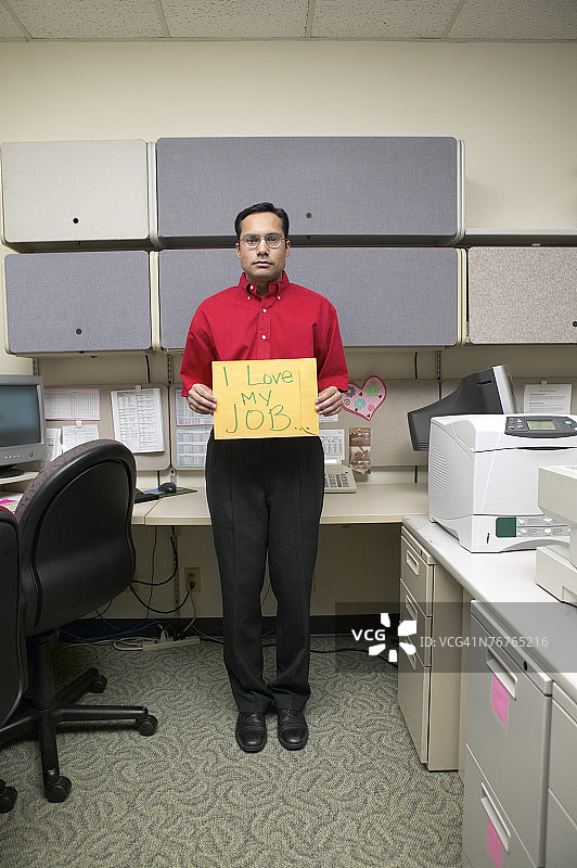 在办公室里举着“我爱我的工作”标语的男人图片素材