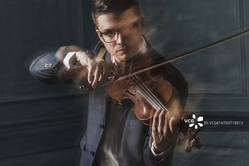 自信的小提琴手靠墙拉小提琴的模糊动作图片素材
