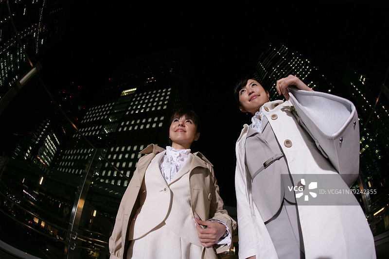两个女人站在晚上的街上，低角度图片素材
