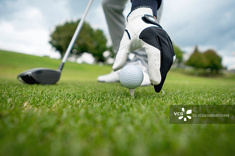 高尔夫球手将球放在高尔夫球座上的特写镜头图片素材