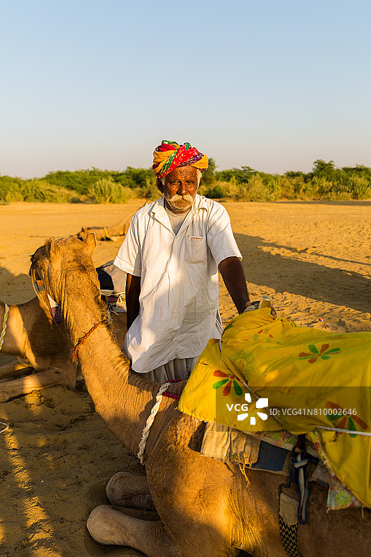 一名拉贾斯坦邦老人在Jaisalmer沙漠中骑着骆驼，印度图片素材