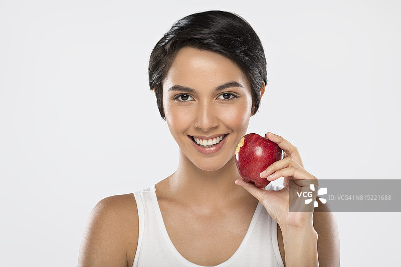 一个年轻美丽的亚洲女人，手里拿着一个白色背景的红苹果图片素材