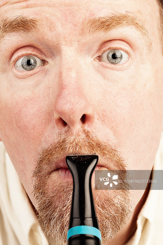 一名男子正在用电动修眉机修胡子图片素材