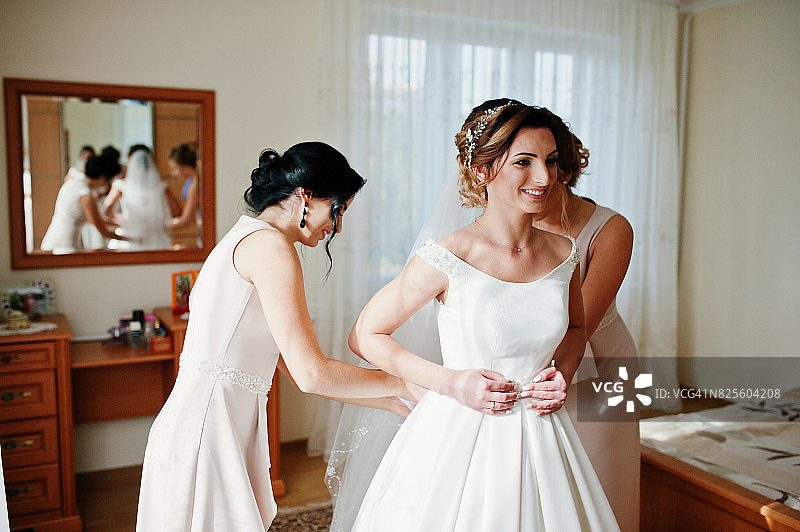 伴娘帮助美丽的新娘打扮，为她的婚礼做准备。图片素材