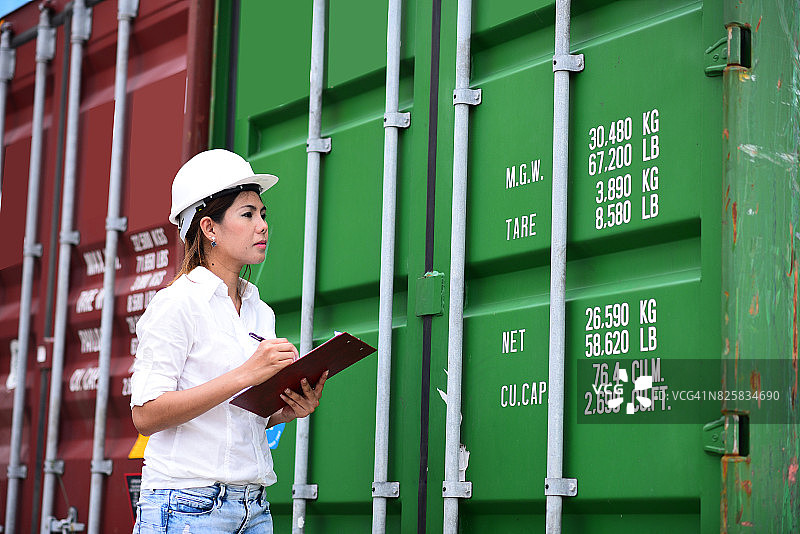 亚洲女码头工人在集装箱前签署或写文件到卡车图片素材
