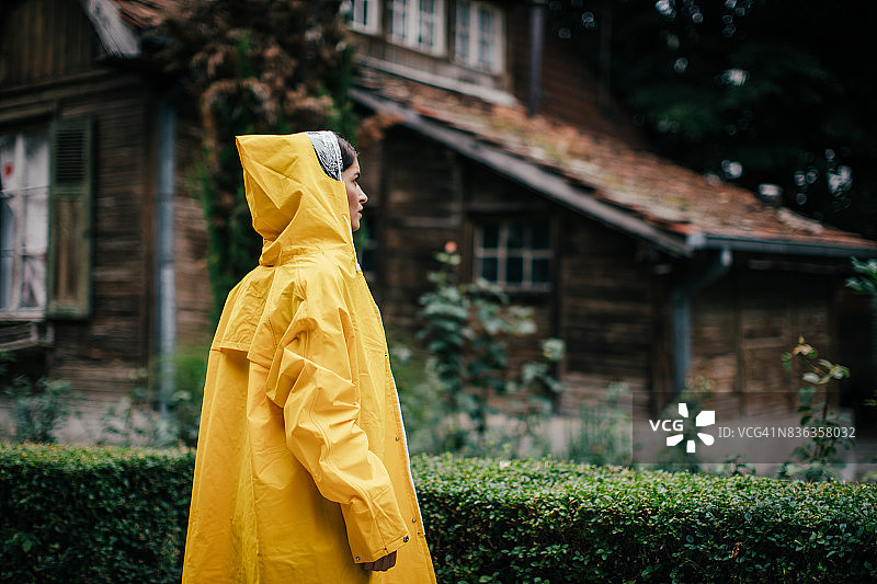 一个穿着黄色雨披的女人在享受天气图片素材