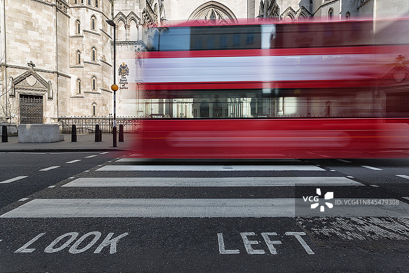 红色伦敦公共汽车在伦敦皇家法院前穿过人行道图片素材