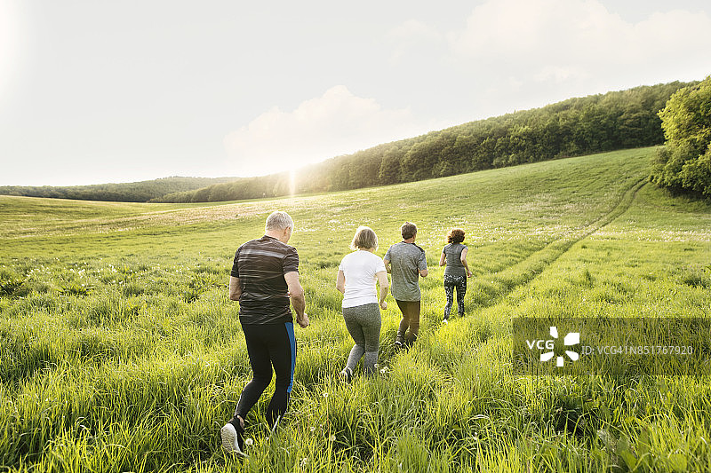一群老年人在绿色的山上跑步。图片素材