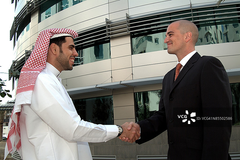 两个年轻的阿拉伯专业人士在阿联酋的迪拜握手。图片素材
