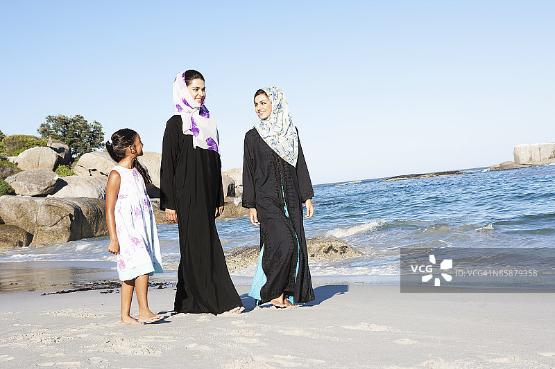 两个阿拉伯女人和一个女孩在海滩上。图片素材