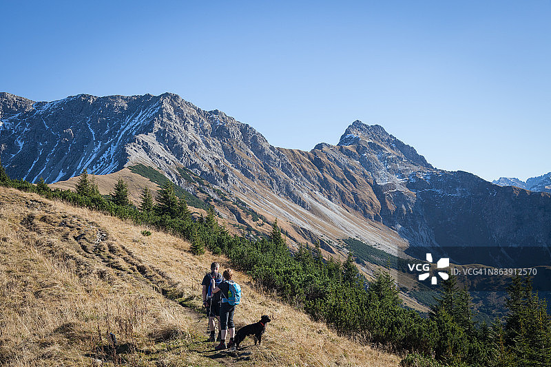 夫妇和狗在美丽的阿尔高阿尔卑斯山徒步旅行图片素材