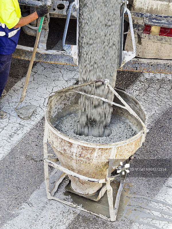 高角度视图的卡车水泥搅拌机卸载混凝土上的桶井架在一个工作。西班牙图片素材