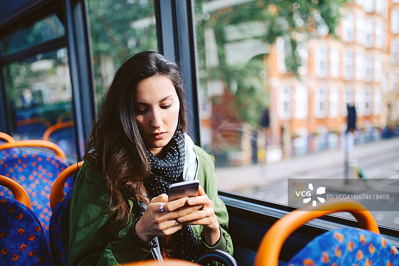 在伦敦，一名年轻女子在公交车上发短信图片素材