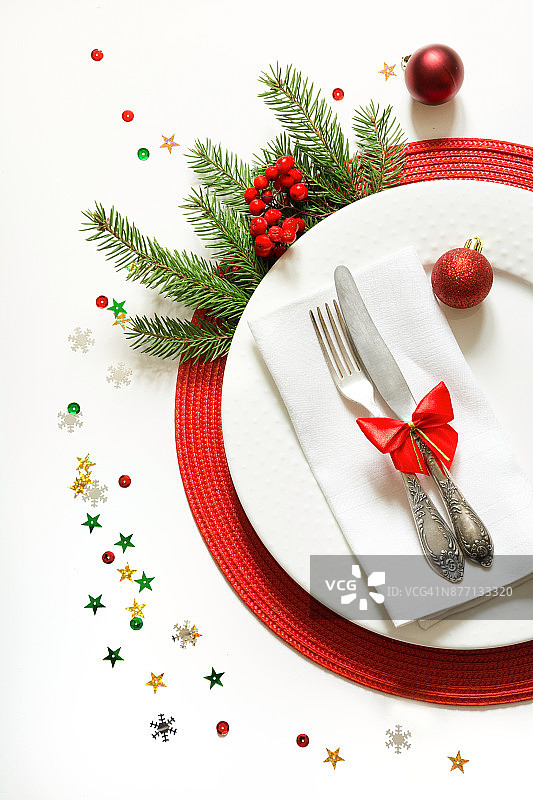 圣诞餐桌的白色餐具，银器和红色的装饰在白色的背景。前视图。图片素材