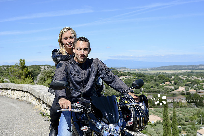 快乐的年轻摩托车夫妇在夏天骑摩托车。图片素材