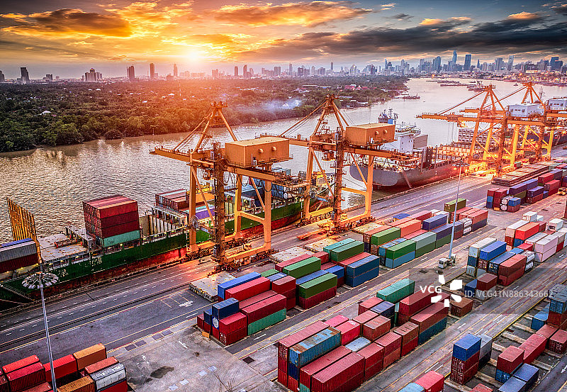 物流与运输的集装箱货轮和货机与工作起重机桥在日出船厂，物流进出口和运输行业背景图片素材