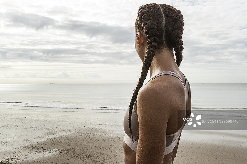 年轻的女性跑步者发辫从海滩望向大海图片素材