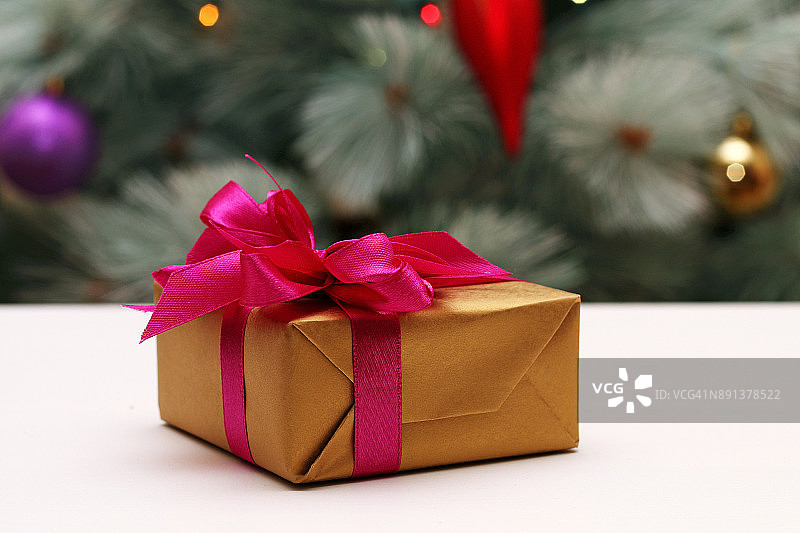 圣诞树背景上的白色桌子上有蝴蝶结的礼盒图片素材